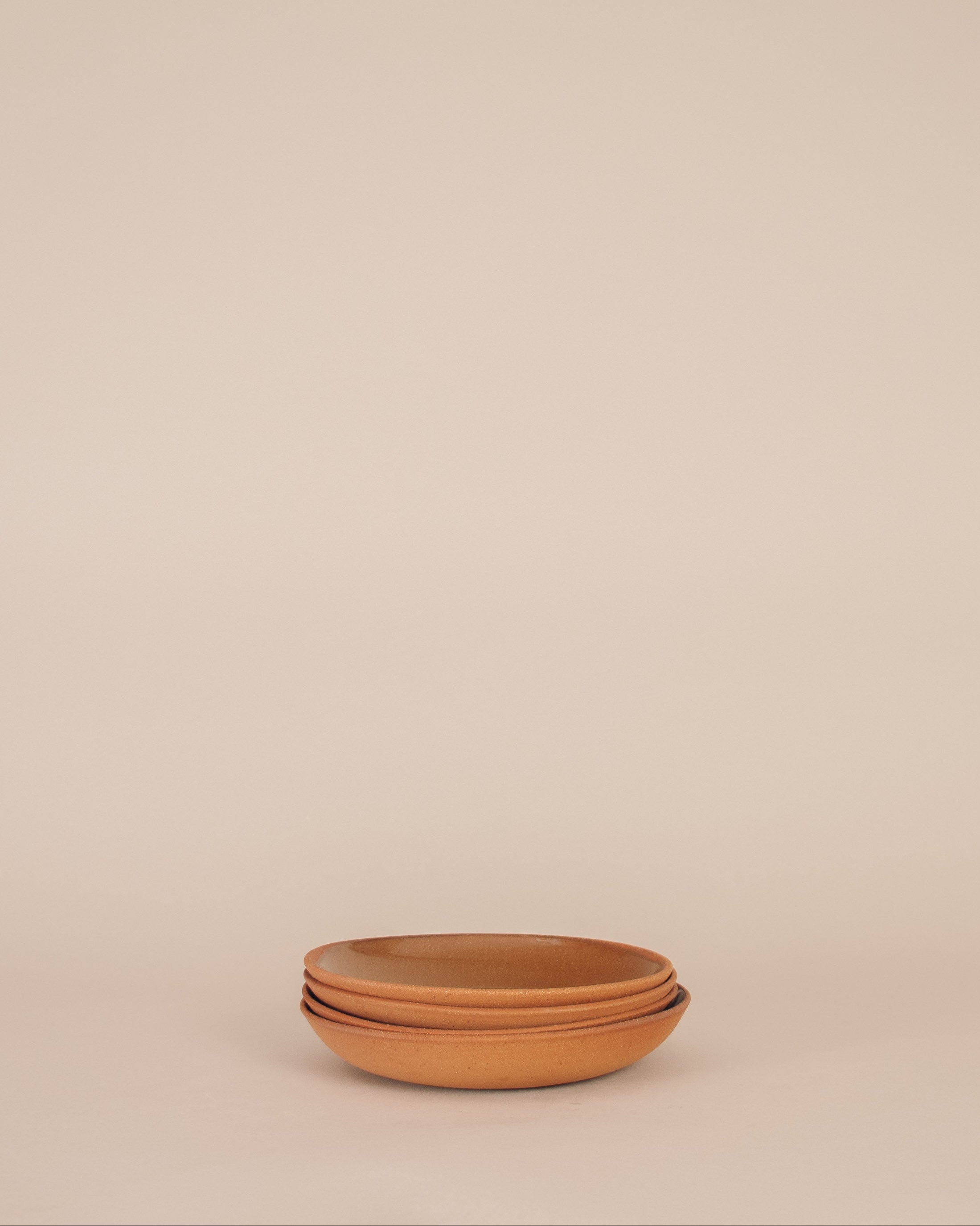 Stack of terracotta bowls on a beige background