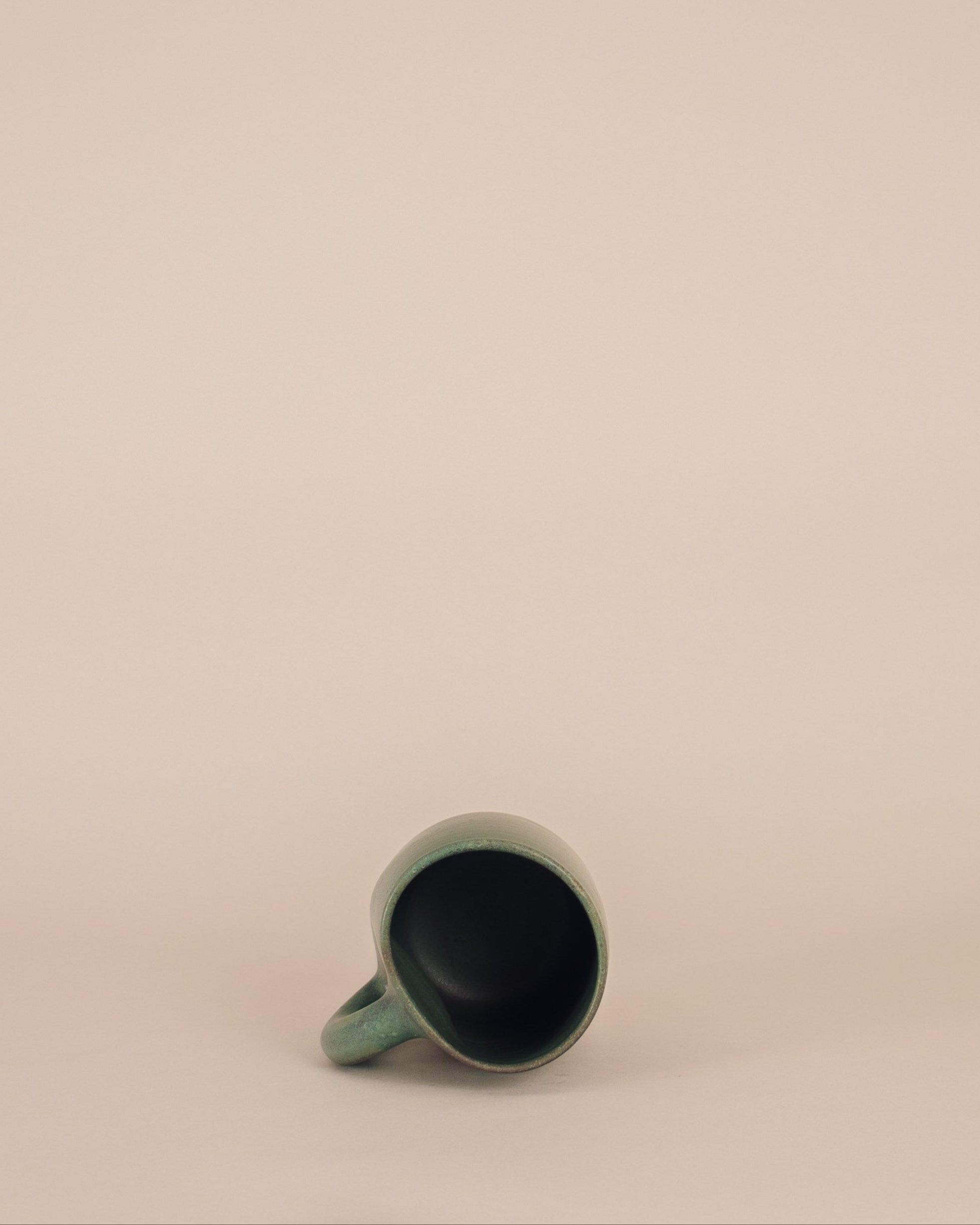 Green ceramic mug on a beige background