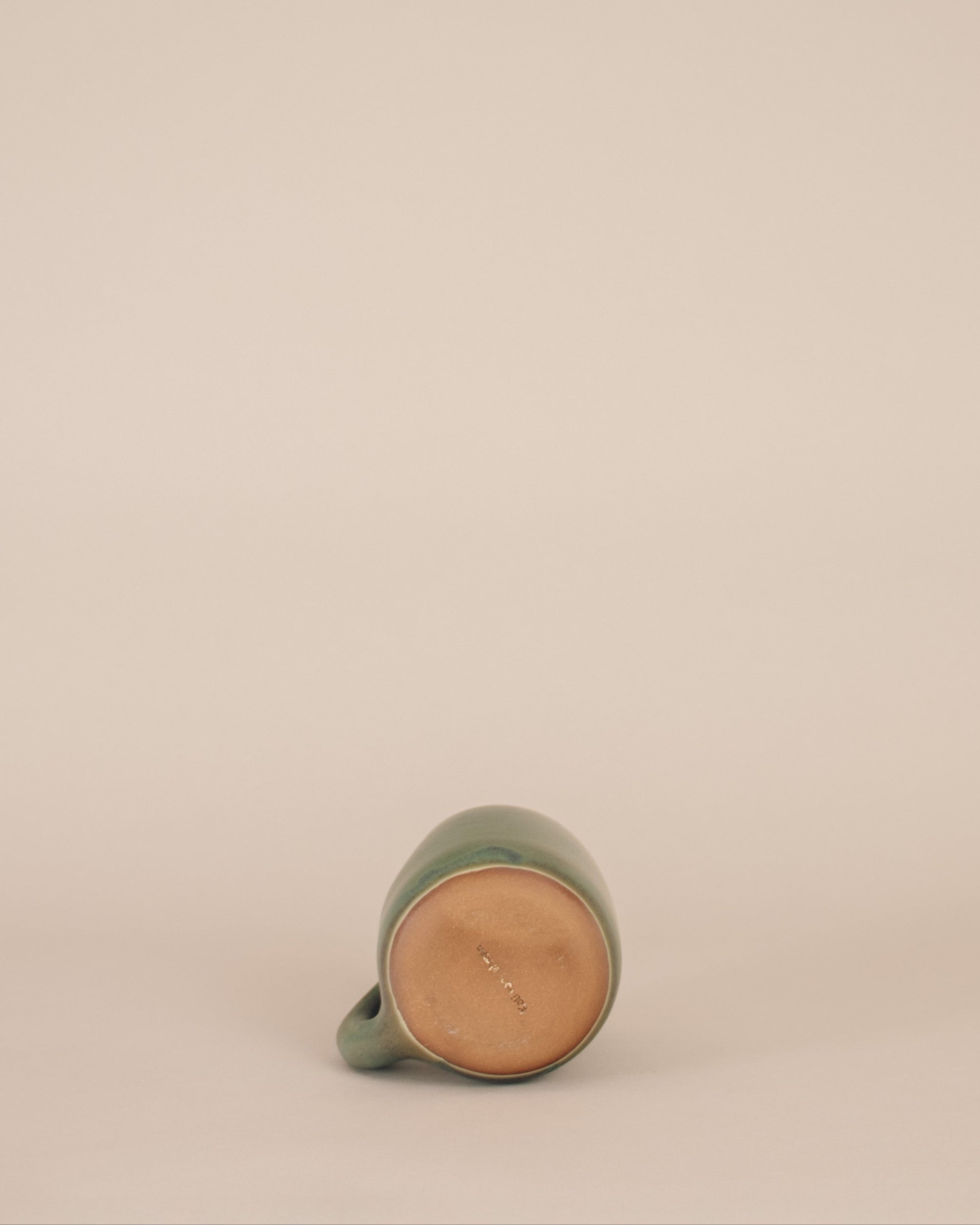 Green ceramic mug on a beige background